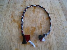 a red, white and black headband on a wooden table with two small pieces of fabric