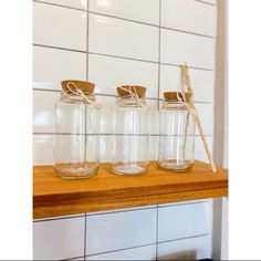 three glass jars with twine and rope tied to them on a wooden counter top