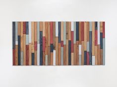 a piece of art made out of wood with different colored strips on the wall behind it