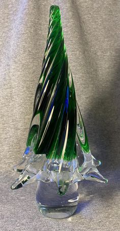 a green glass christmas tree sitting on top of a clear base with black and white stripes