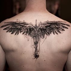 the back of a man's shoulder with a cross and wings tattoo on it