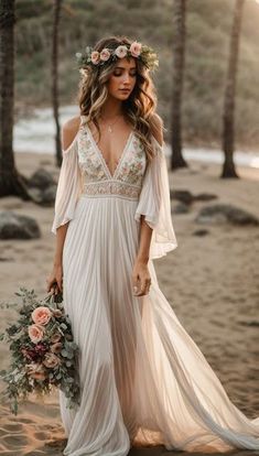 a woman in a white dress is standing on the beach with flowers and holding a bouquet