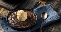 a chocolate dessert with ice cream in a cast iron skillet on a wooden table