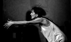 black and white photograph of a woman in motion holding a tennis racket with both hands