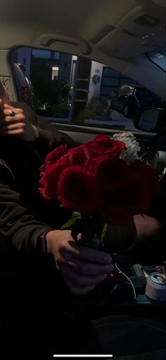 a man sitting in the back seat of a car with a bouquet of roses on his lap