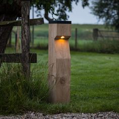 a wooden post with a light on it in the grass