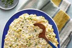 a blue plate topped with macaroni and cheese next to a bowl of green onions