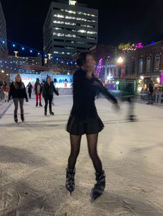 a woman is skating on an ice rink at night with other people in the background