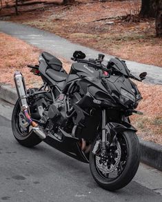 the motorcycle is parked on the side of the road next to the grass and trees