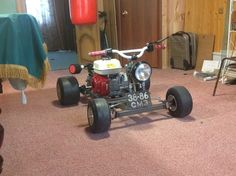 a small four wheeled vehicle is parked in a room with pink carpet and wooden walls