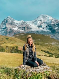 a woman sitting on top of a rock in the mountains