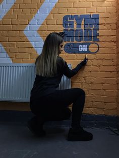 a woman is sitting on the floor with her legs crossed and writing on a wall