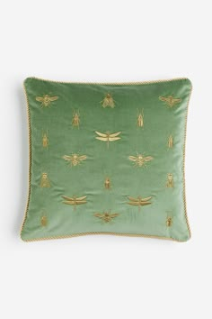 a green pillow with gold bees on it