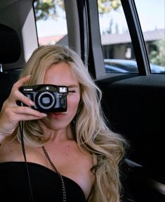 a woman taking a photo in the back seat of a car with a digital camera