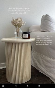 a bed with a white comforter next to a table with a jar on it