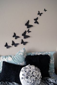 a bed topped with lots of pillows and butterflies on the wall