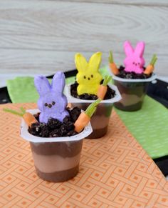 three small plastic cups filled with dirt and decorated like easter bunnies sitting on top of a table