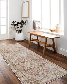 a wooden table sitting on top of a hard wood floor next to a white wall