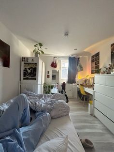 a bed room with a neatly made bed next to a dresser and desk in front of a window