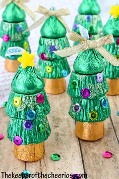 green plastic christmas trees with buttons and bows on them are sitting on a wooden table