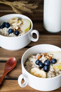 two white bowls filled with oatmeal and fruit