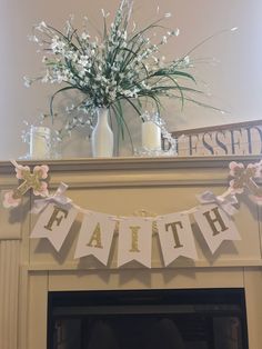 a mantle decorated with flowers, candles and a banner that says faith above it is a vase filled with baby's breath