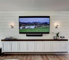 a flat screen tv mounted to the side of a white wall in a living room