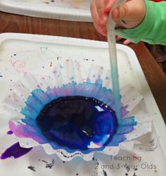 a child is painting with blue and purple paint