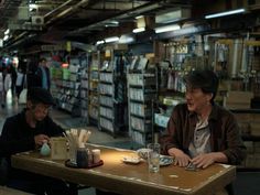 two people sitting at a table in a book store