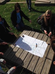 several people sitting around a wooden table with a kite on it and one person holding a string