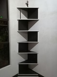 a black and white book shelf sitting in the corner of a room next to a window