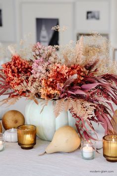 a vase filled with lots of flowers next to candles and other items on a table