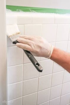 a person in white gloves and rubber gloves is cleaning a tile wall with a brush