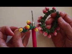 two hands are working on a crochet wreath