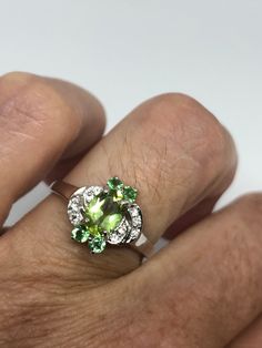 Rich and very bright Peridot, green chrome diopside white white sapphire ring Sterling silver with rhodium finish Size 6.75 can be sized by my jeweler. His service charge is $10-$20 All rings are shipped in a nice gift box. Check out our over a THOUSAND great reviews Engraving is $4 per letter and is not always perfect depending on the piece. It can take a few days if the jeweler is busy. This is payable to Paypal Judithsltd@gmail.com Green Diamond Gemstones For May Birthstone, Green Peridot Multi-stone Jewelry, Green Sterling Silver Gemstones With Accent Stones, Green Peridot Birthstone Gemstones, Green Peridot Gemstones As Birthstones, Green Tsavorite Jewelry With Accent Stones, Green Peridot Jewelry With Center Stone, Green Peridot Jewelry With Prong Setting, Green Gemstones For Promise Rings