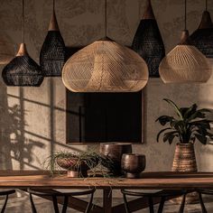 a wooden table topped with vases and plants next to a wall covered in hanging lights