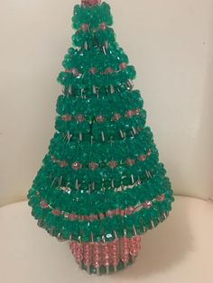 a green beaded christmas tree sitting on top of a table