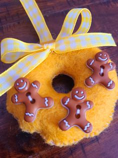 a yellow donut decorated with gingerbreads on top of a wooden table next to a ribbon