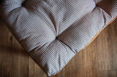 a close up of a pillow on a wooden floor with a black and white striped cover