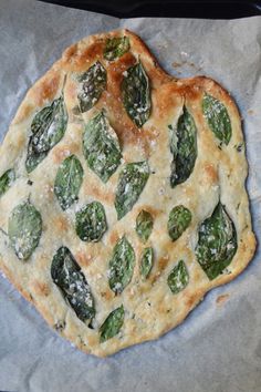 a pizza sitting on top of a piece of paper covered in cheese and spinach