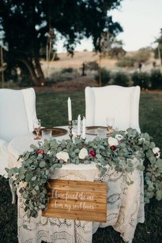 a table with flowers and greenery is set up for an outdoor wedding reception in the grass