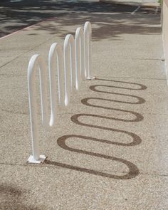 there are several white poles on the sidewalk and one is marked with an o - ring