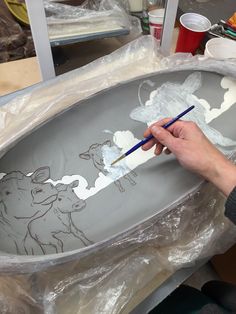 a person is painting a bowl with animals on it in the process of being finished