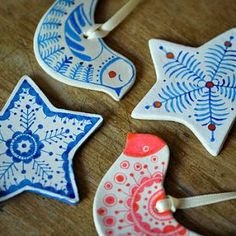 four ceramic ornaments on a wooden table with string and bead sprinkles