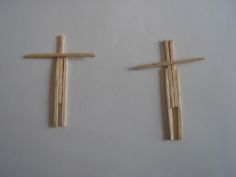 two wooden crosses sitting next to each other on a white surface with wood sticks sticking out of them