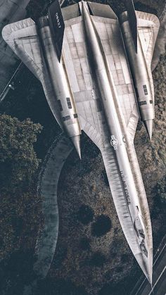 an aerial view of a fighter jet flying in the sky over some grass and trees