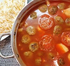 a pot filled with meatballs and tomato soup on top of a table next to rice