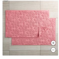 two pink bath mats sitting next to each other on top of a wooden floor,