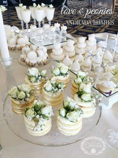 there are many cupcakes on the table with white flowers and candles in front of them