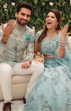 a man and woman sitting on a couch with their hands in the air